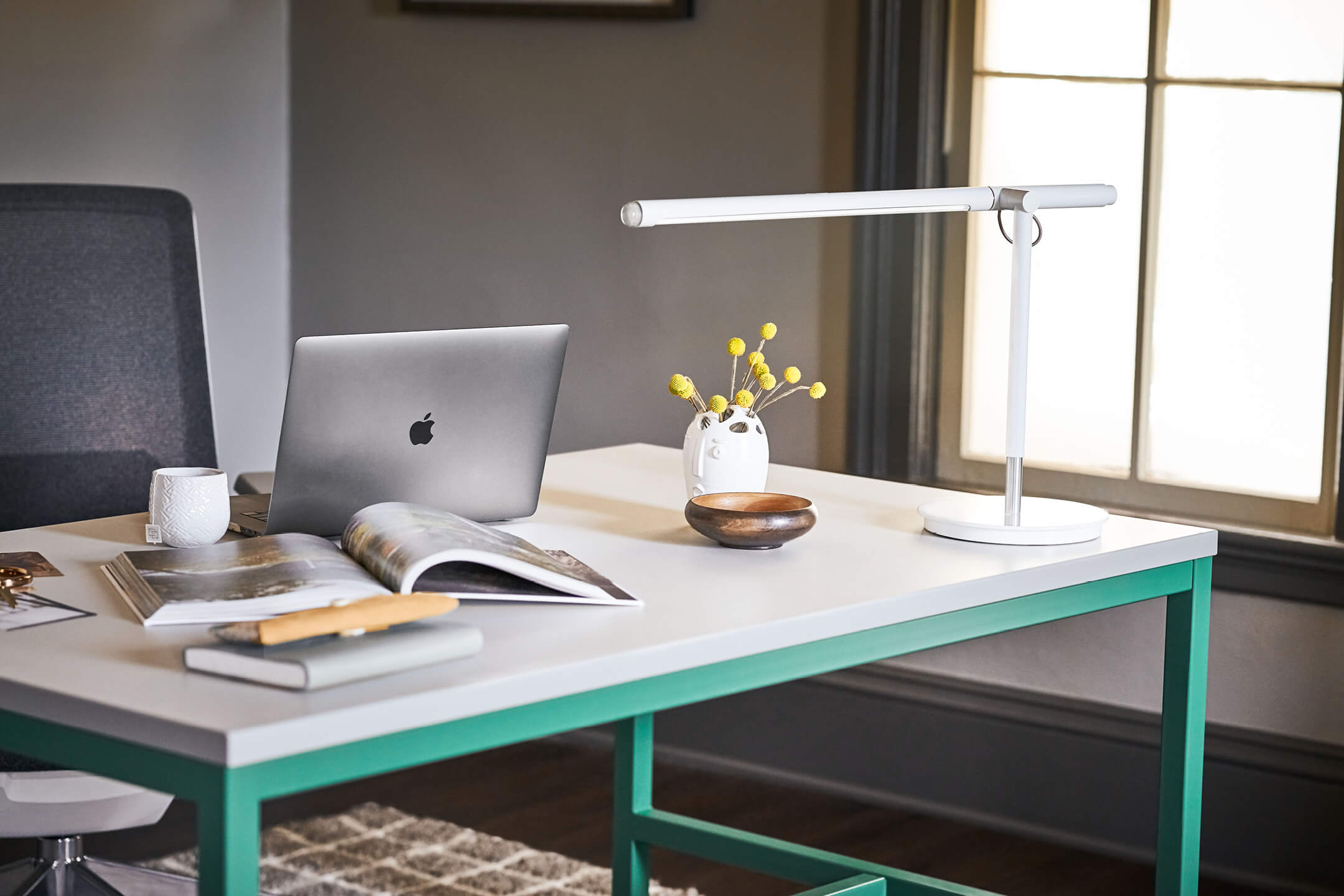 Haworth Pablo Pardo Designer office desk lamp over book on table with office chair at it