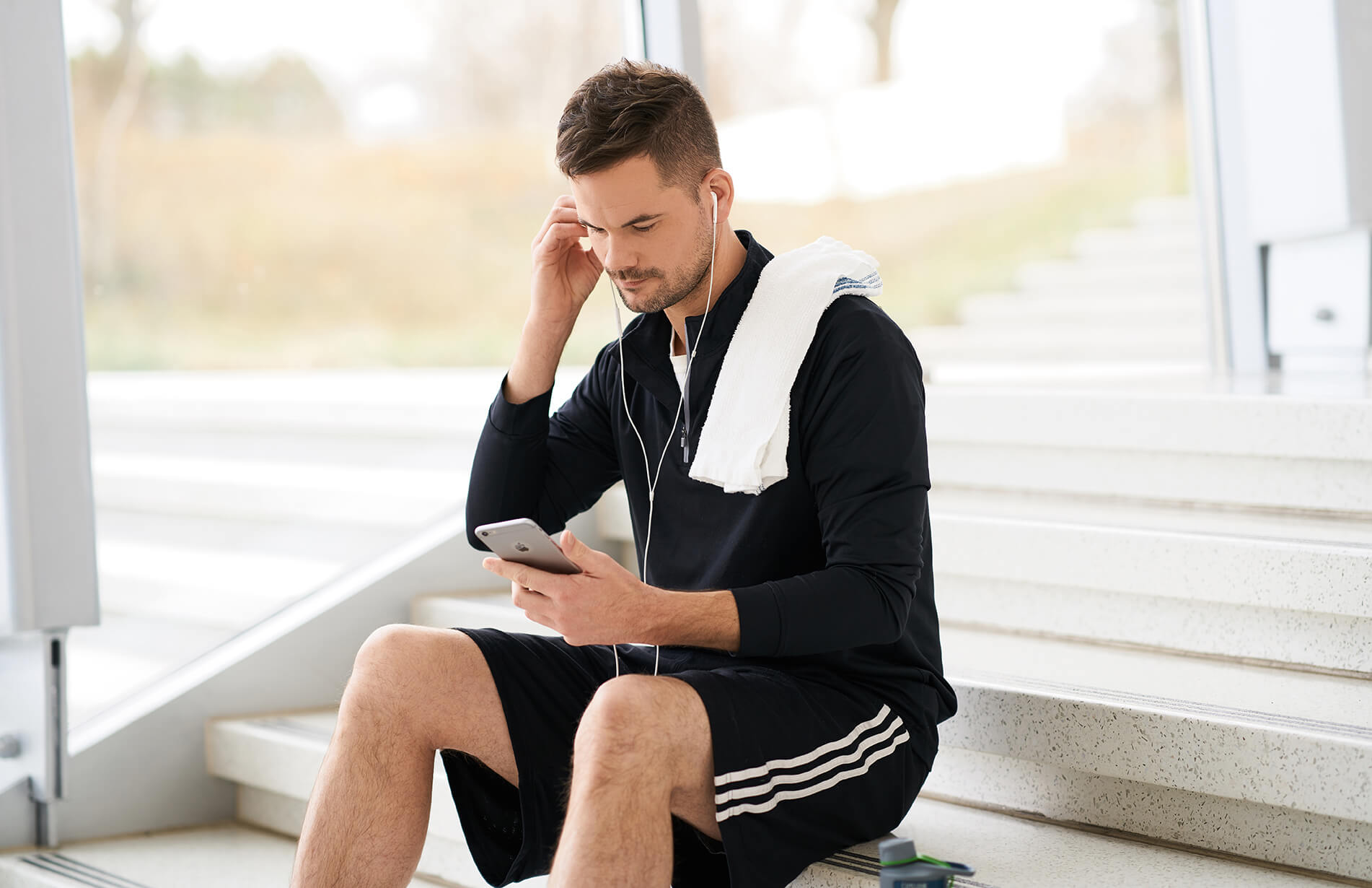 man in exercise clothing sitting on stairs listening to music