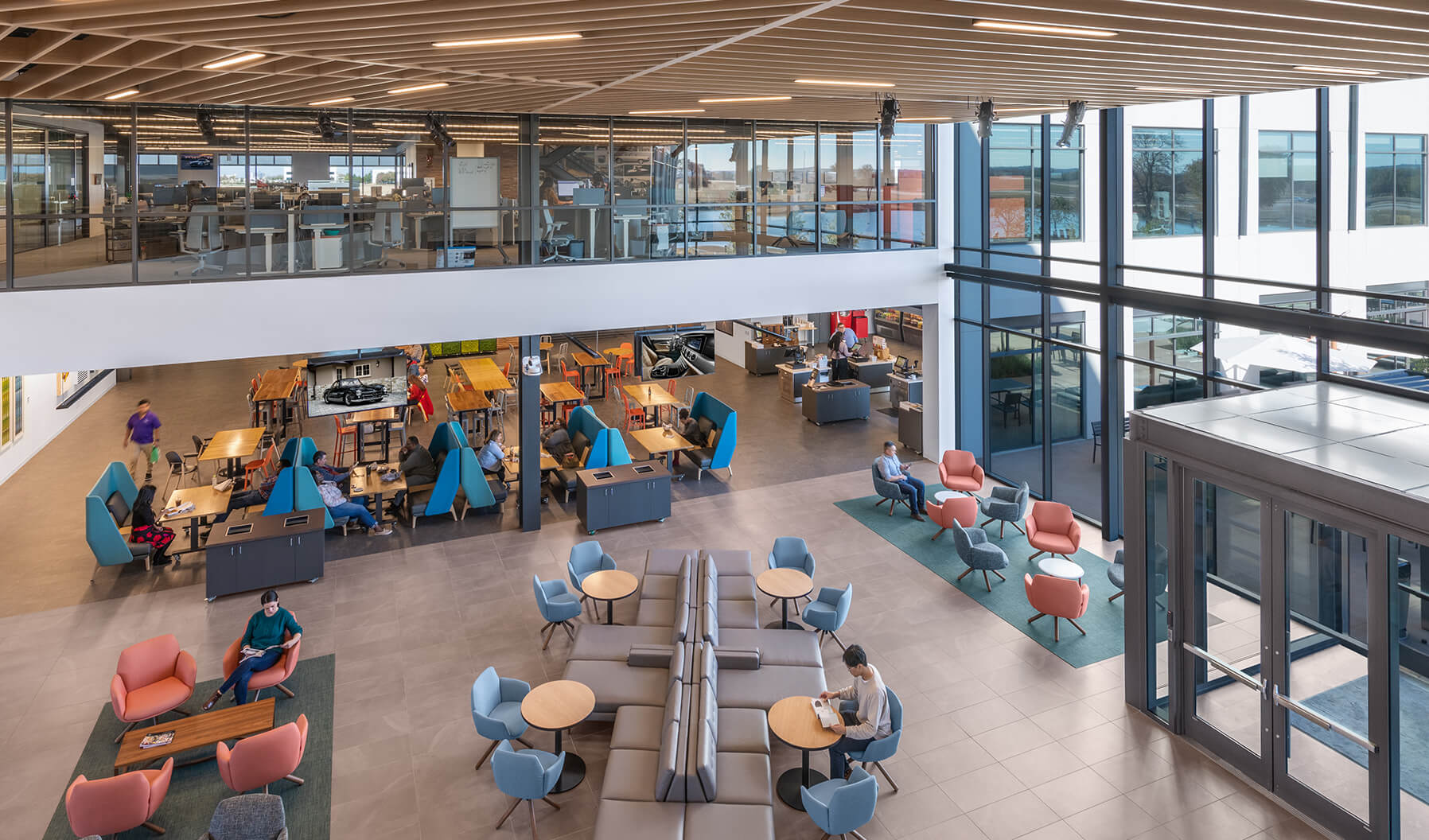 Workstations on the upper level of the building catch a bird’s-eye view of the cafeteria and collaborative area below. The glass allows natural daylight to permeate throughout all aspects of the space.