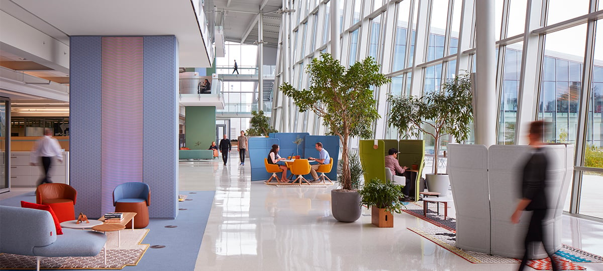 The use of screens, plants, and architectural features create space division and a sense of privacy in a large atrium volume, making this a place where people can comfortably connect.