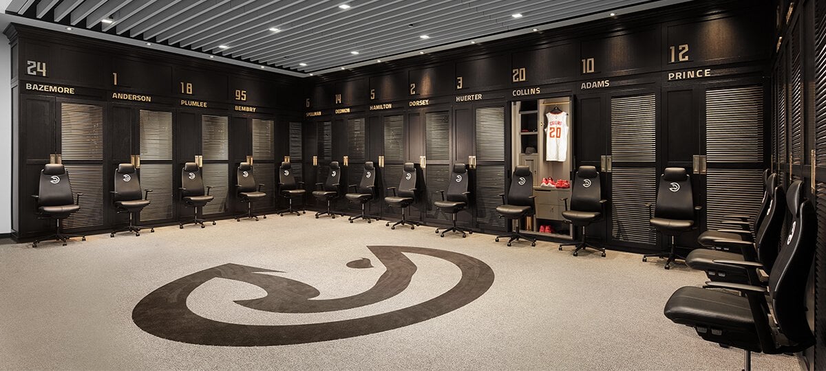 Les vestiaires ont été conçus pour recréer l’ambiance d’un club de gentlemen privé. La palette de couleurs noir et doré ainsi que les détails sur chaque casier créent un effet élégant, digne d’un décor de film. Afin d’optimiser au maximum le confort des athlètes, tout le mobilier a été pensé en fonction de leur taille. Ainsi, les lavabos ont été surélevés, de plus grandes poignées ont été installées et les casiers ont été disposés dans un espace ouvert. L’espace comprend 18 fauteuils Fern® avec repose-tête, chacun étant réglable en hauteur et brodé du logo des Hawks.