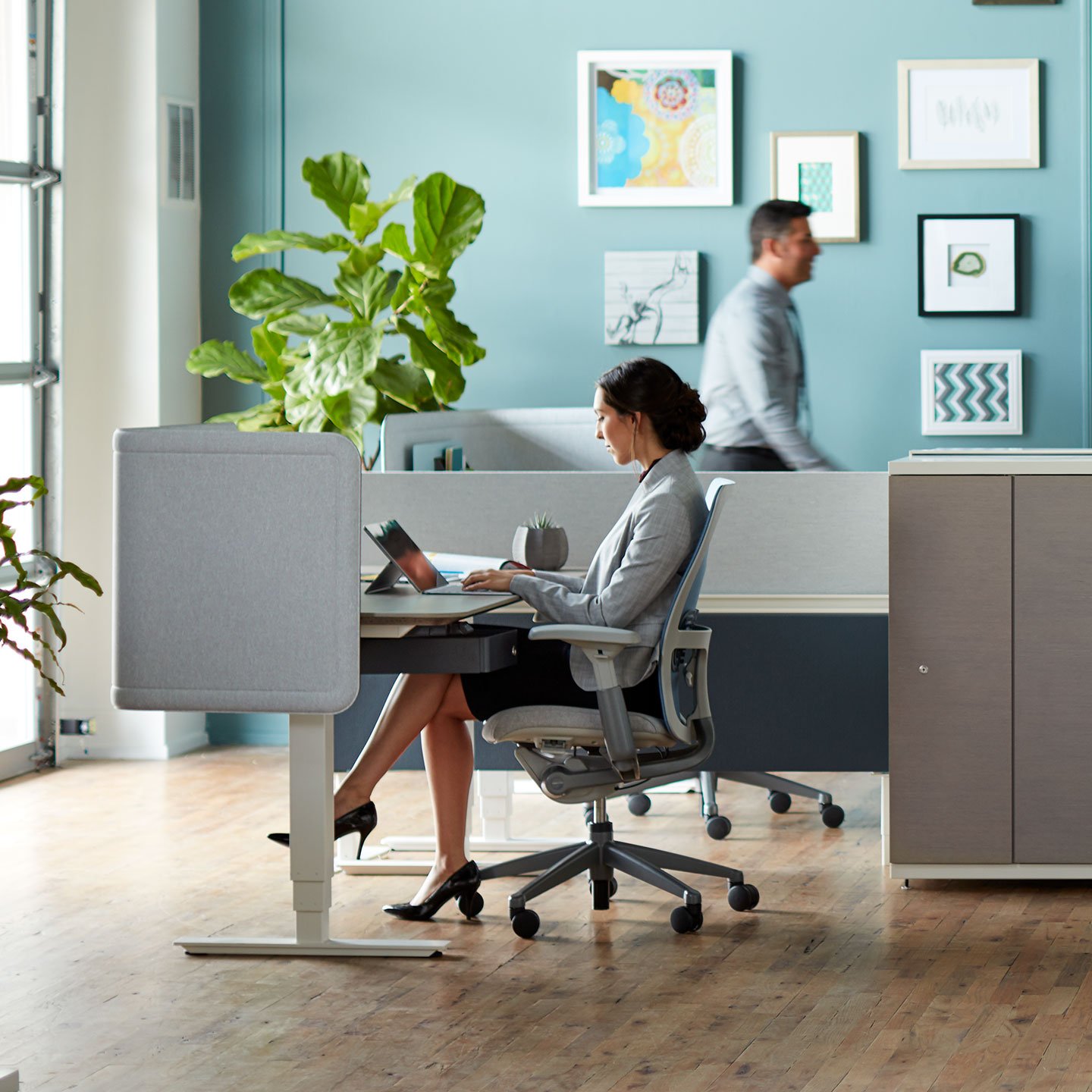 Haworth Compose Connections workspace divider in grey in an office area with employee working at desk