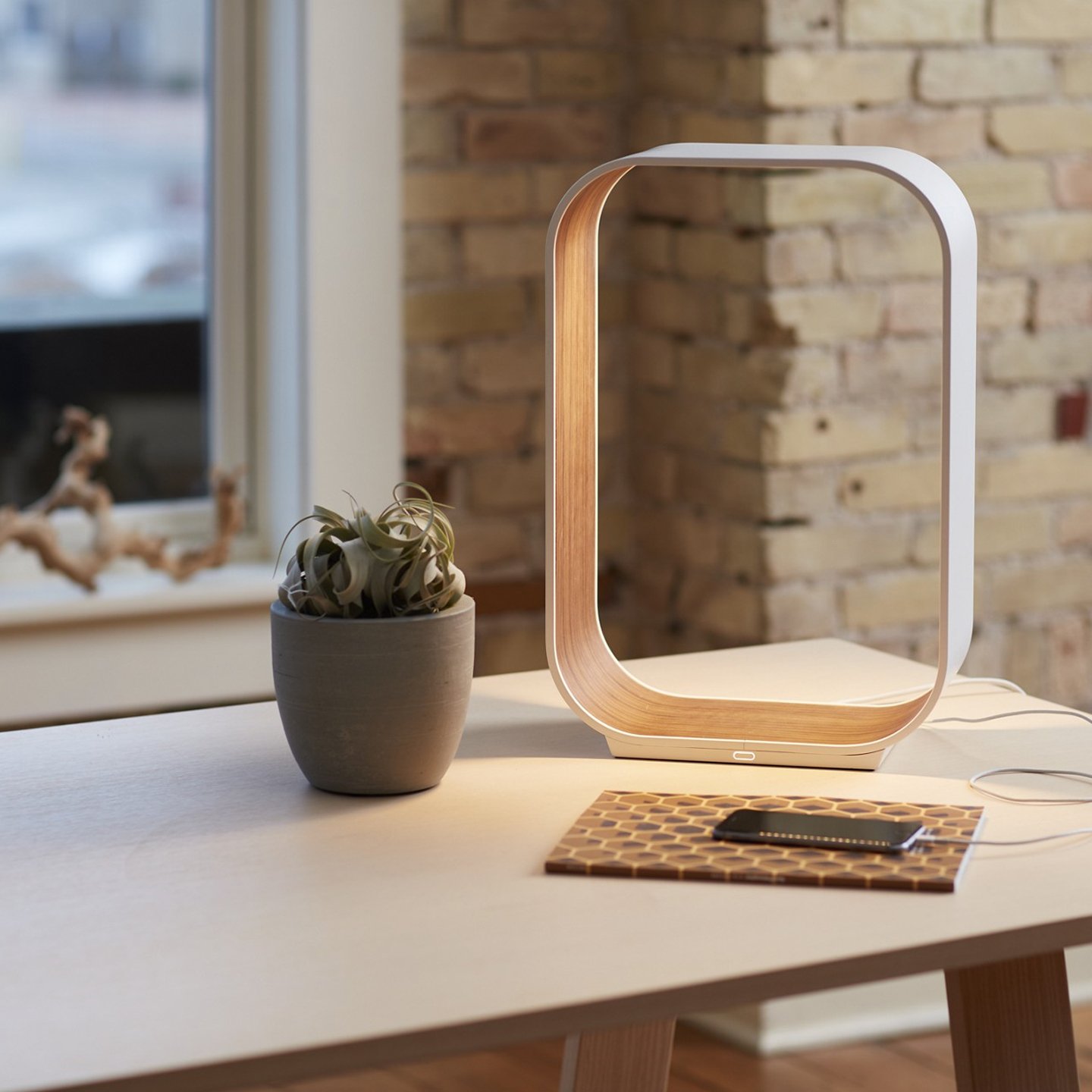 Haworth Contour Lighting in white color and wood finish on office desk with phone and plant