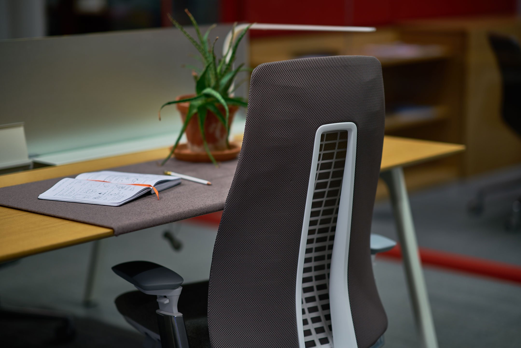 Haworth Fern task chair in dark grey with a desk in a office space