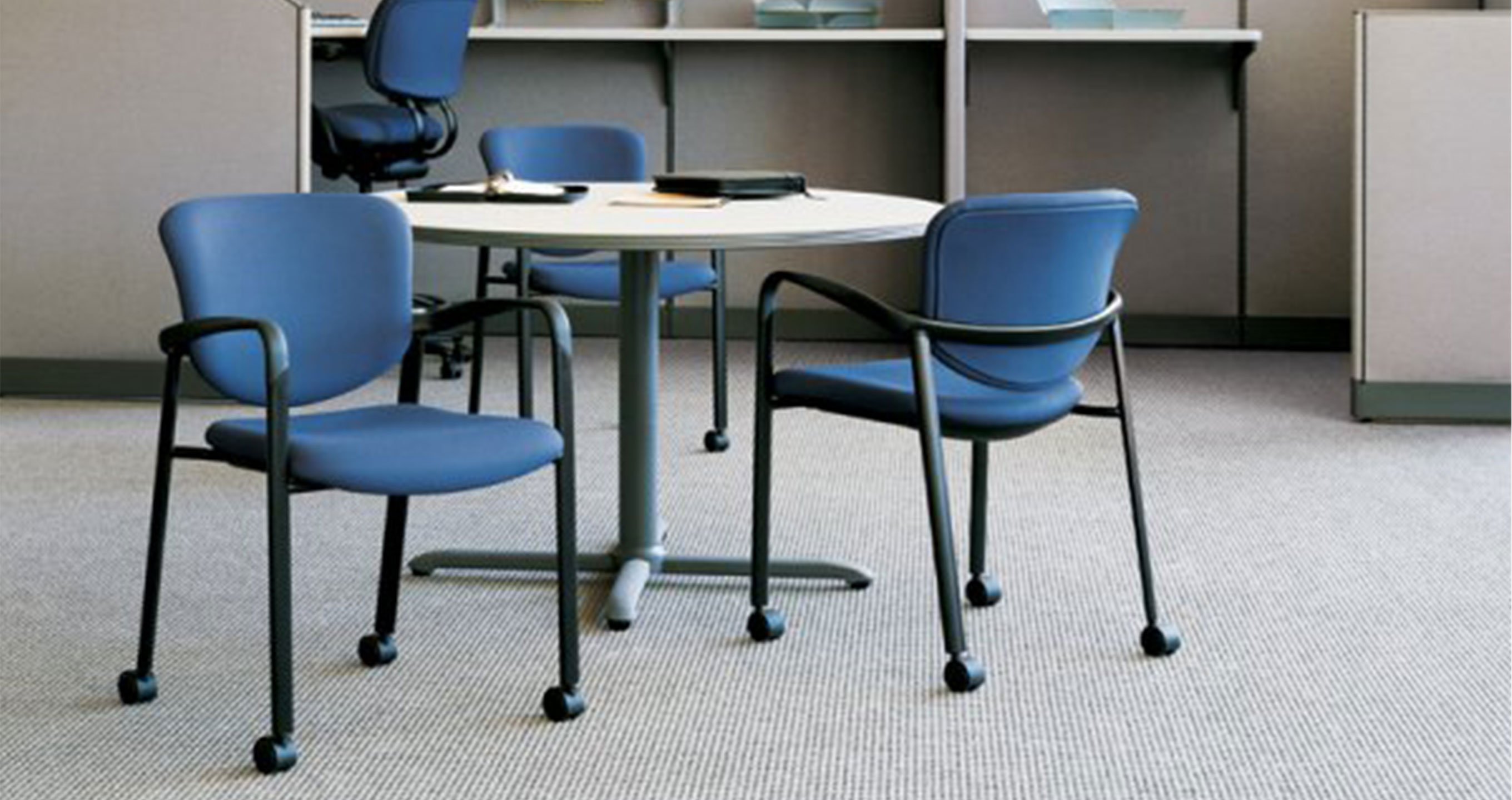Haworth Improv side chair in blue upholstery and wheels in a conference room