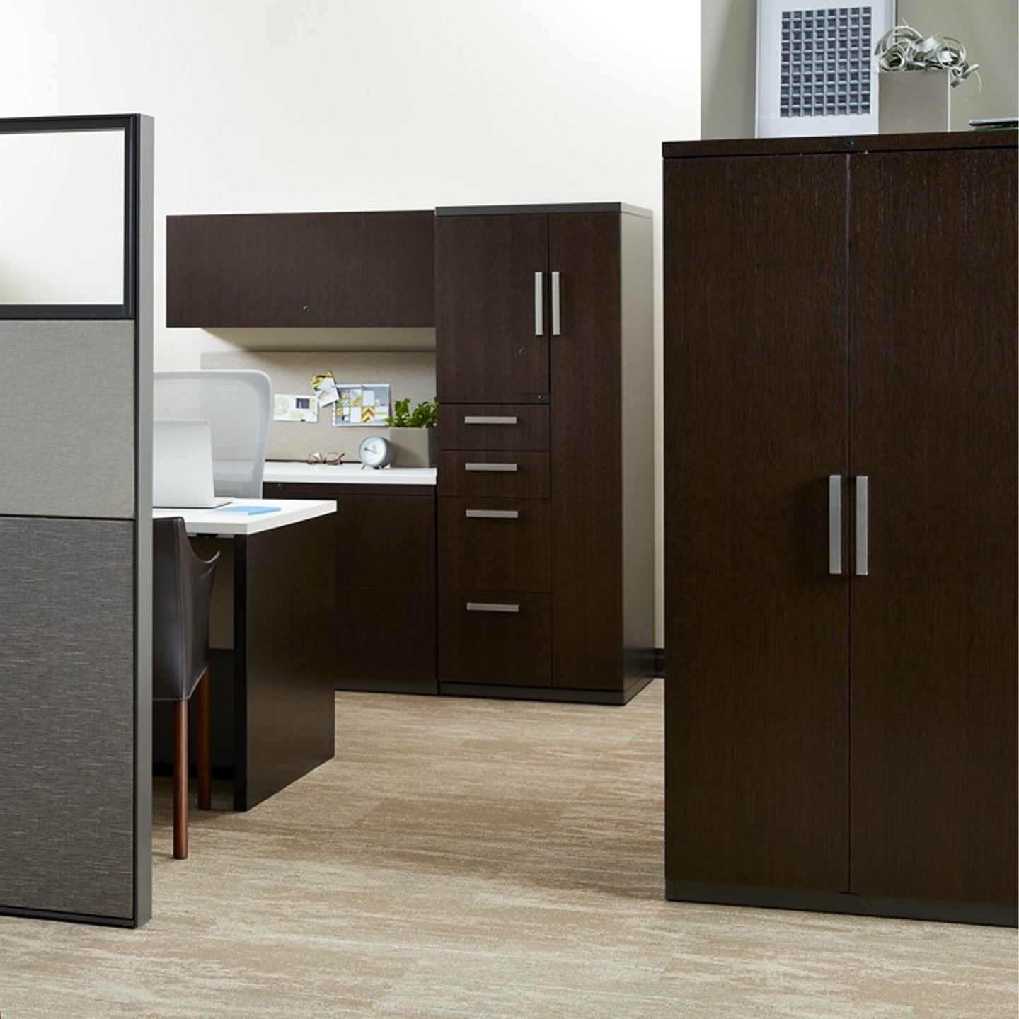 Compose storage unit in dark wood at workstation with classic door handles on cabinets and drawers.