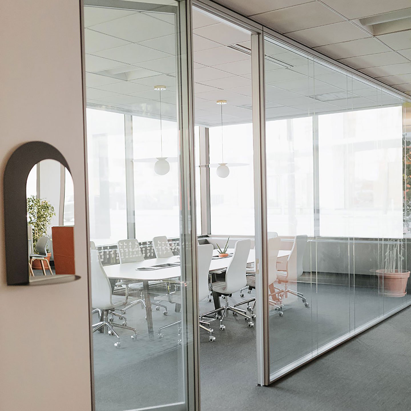 Haworth Enclose Frameless Glass Wall for a office meeting area closed off with white desk and white chairs