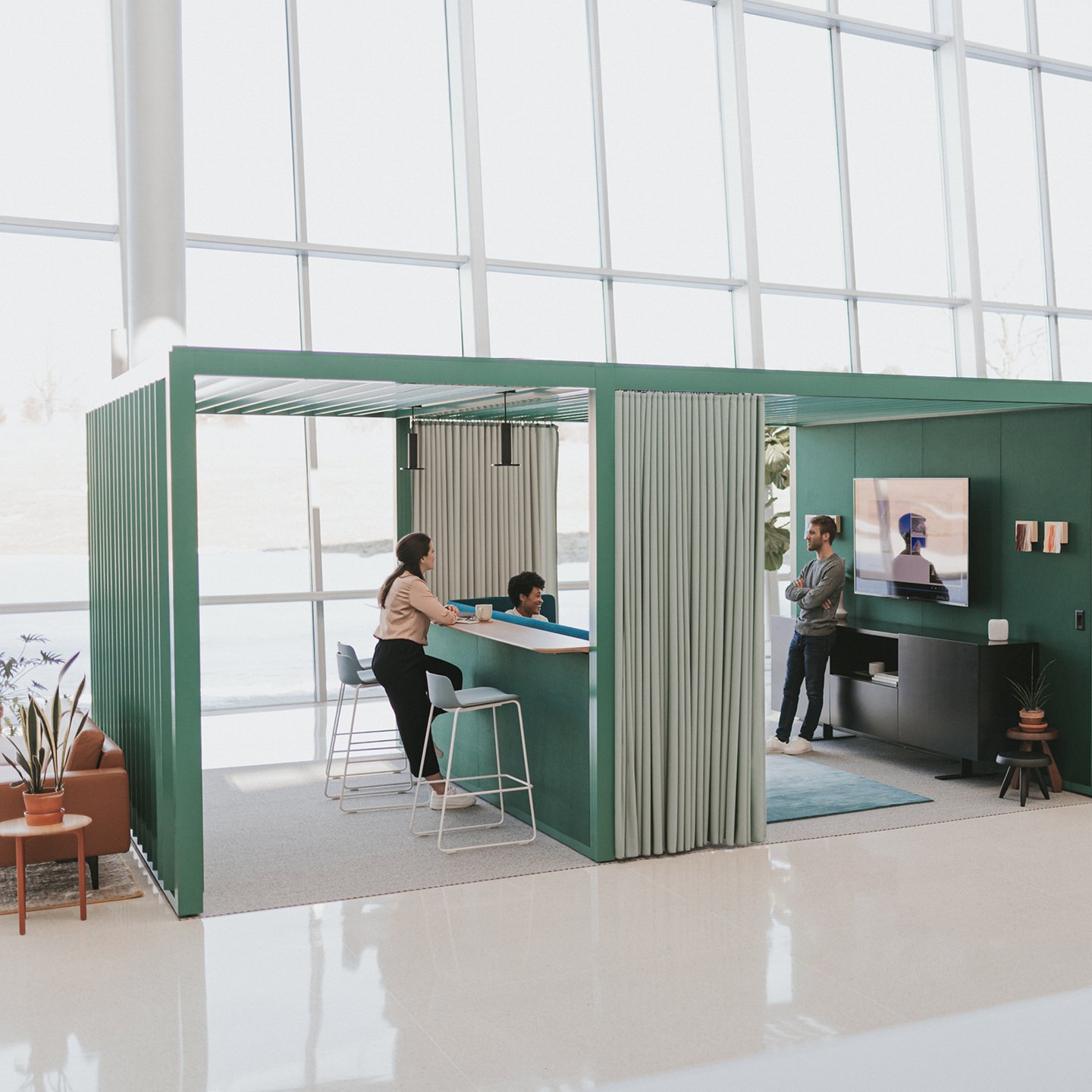 Haworth Pergola Workspace in green trim with green curtain with tall table on wall with employees working inside open office space